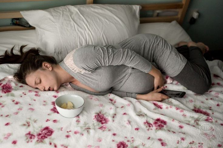 a woman laying in bed with her head on the pillow while holding a cell phone