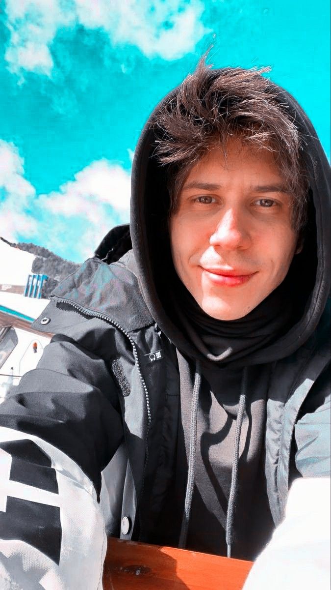 a young man sitting on top of a snowboard in front of a blue sky