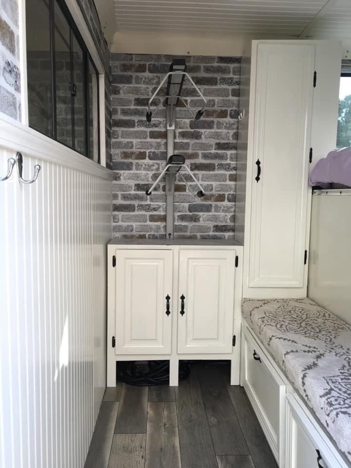 a room with white cabinets and wooden flooring next to a brick wall in the background