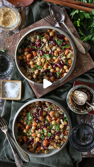 two pans filled with food sitting on top of a table next to spoons