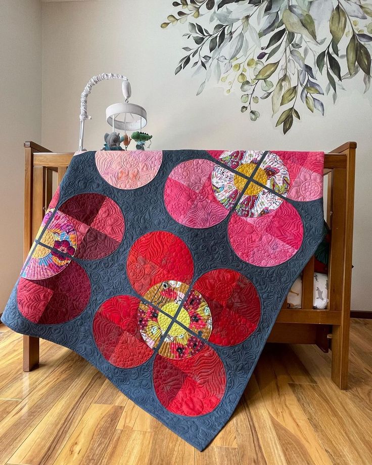 a quilted blanket on top of a wooden chair in front of a wall hanging