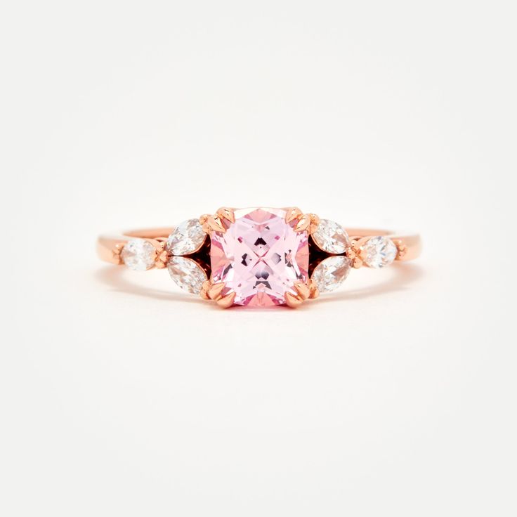 Custom designed by Amelie, and exclusive to Identity Diamonds Recycled metal Set in the center with a lovely 1.25ct* (6mm) cushion cut lab-grown rosé sapphire With a blush hue reminiscent of the color of morganite, our rosé sapphire features a slightly more saturated pink, and it offers a much better durability than morganite, making it ideal for an engagement ring! Available in two different tones: a hint of peach, or a hint of lavender in it Features six marquise shaped lab-grown diamonds, for Rose Gold Cushion Cut Ring With Accent Stones, Rose Gold Square Cut Promise Ring, Rose Gold Rings With Asscher Cut And Accent Stones, Luxury Rose Gold Square Cut Ring, Rose Gold Square Cut Wedding Rings, Spinel Engagement Rings, Montana Sapphire Engagement, Montana Sapphire Engagement Ring, Engagement Ring Pictures