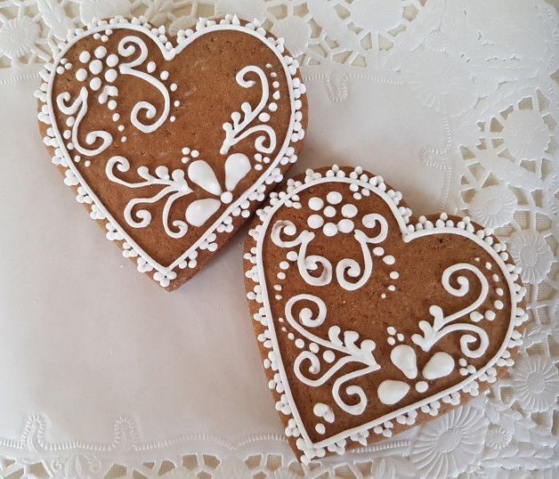 two heart shaped cookies sitting on top of a white doily covered tablecloth,