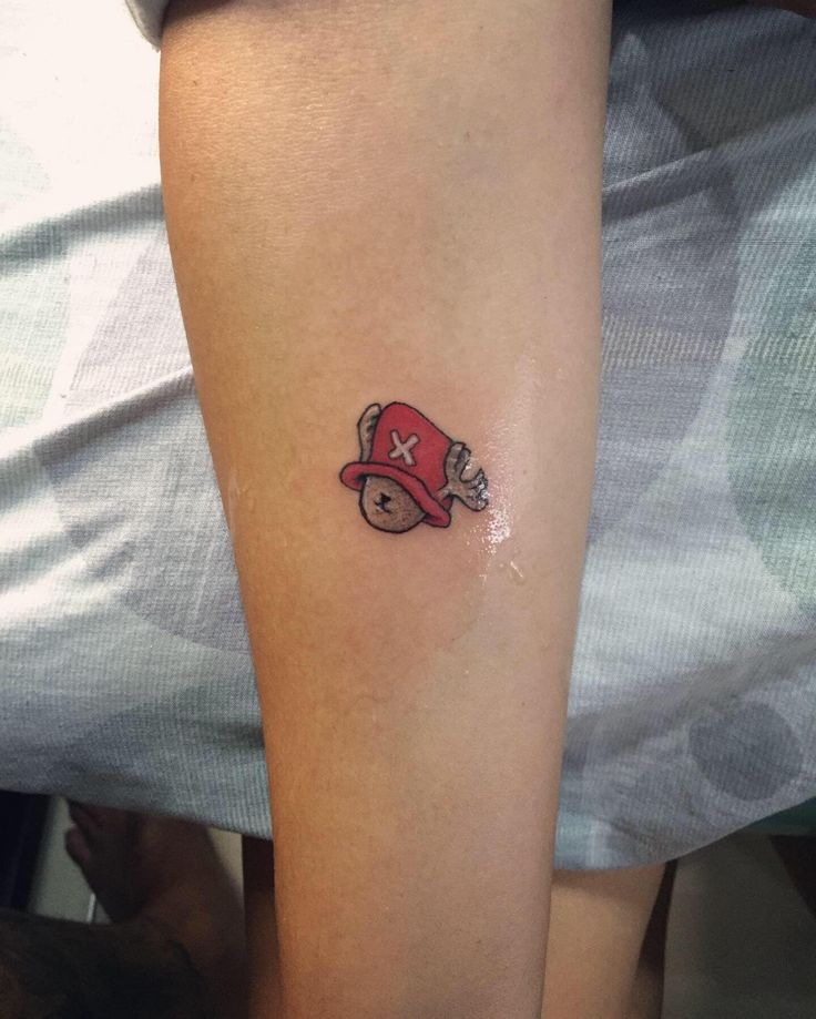 a small tattoo on the leg of a person wearing a red hat and baseball cap