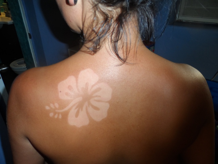 the back of a woman's head with a white flower painted on her left shoulder