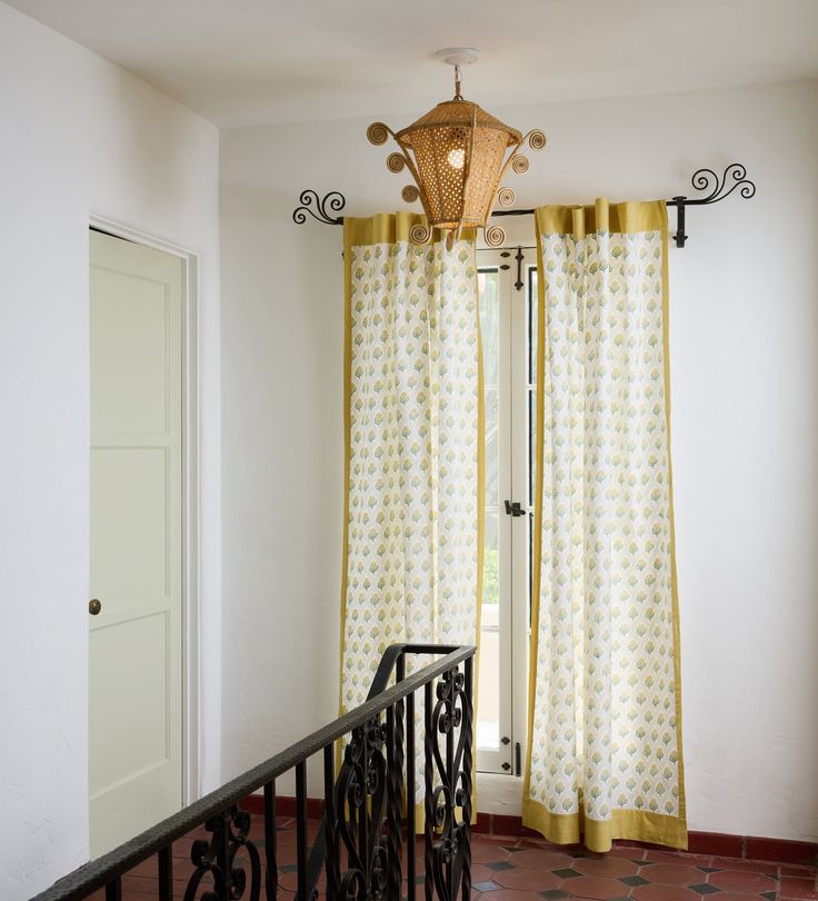 a balcony with curtains and a chandelier hanging from the ceiling, next to a door