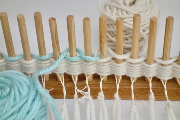 several skeins of yarn sitting next to each other on a wooden rack with knitting needles