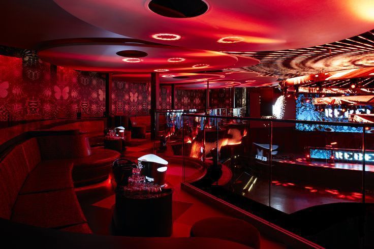 a dimly lit room with red lighting and black furniture in the center, along with many circular lights on the ceiling