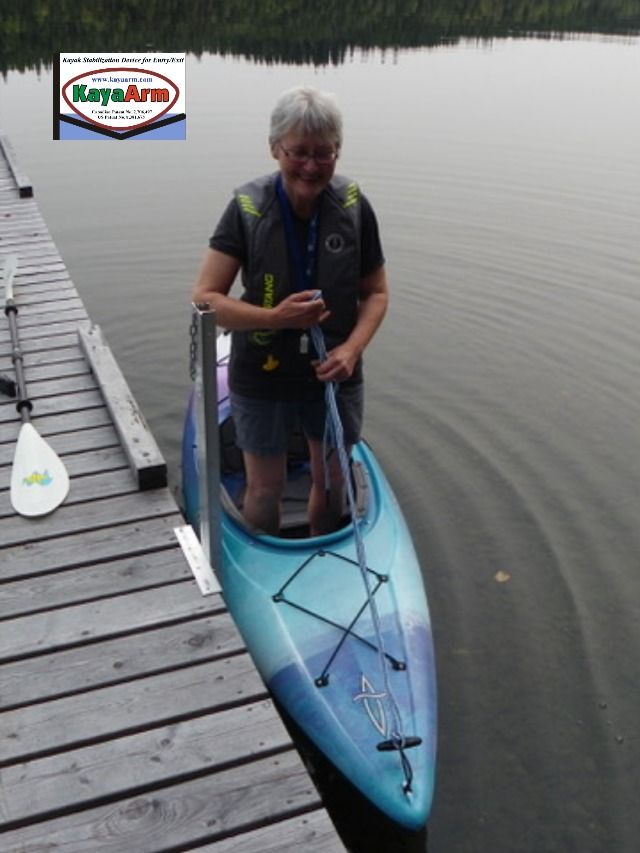 a woman standing on the end of a blue kayak