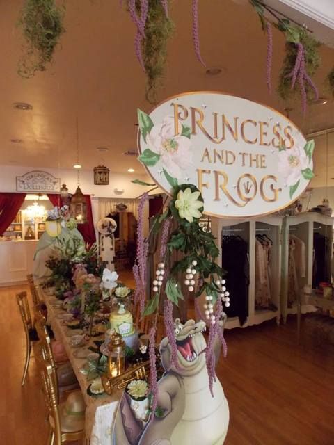 a sign that says princess and the frog on top of a table filled with flowers