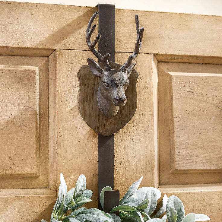 a deer head mounted to the side of a wooden door with plants growing on it