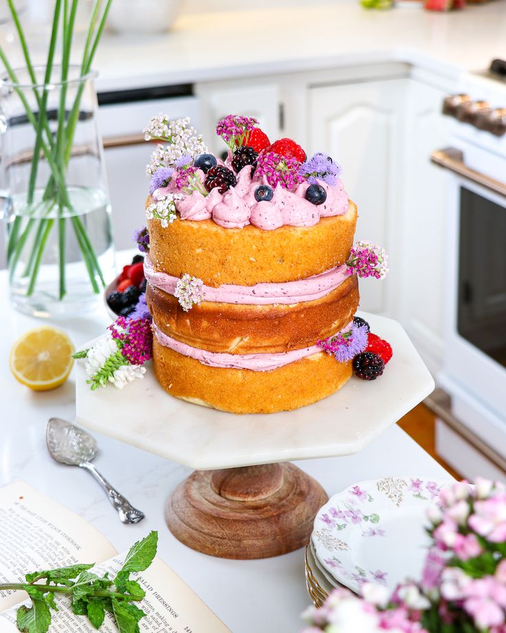 a three layer cake sitting on top of a white plate next to a vase filled with flowers