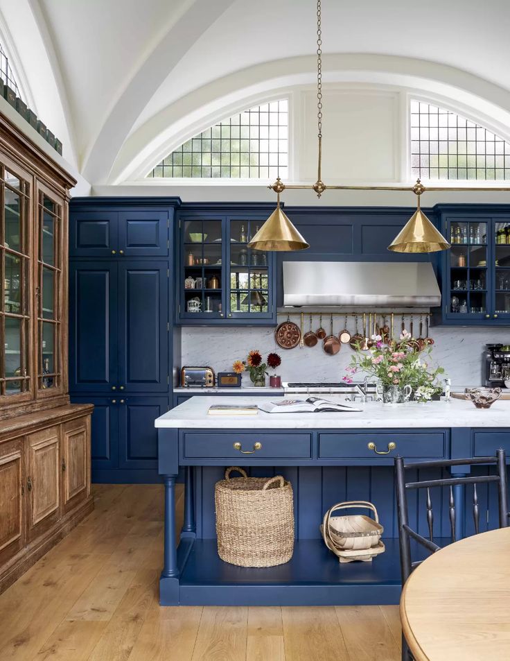 a kitchen with blue cabinets and an island in the middle is seen from across the room