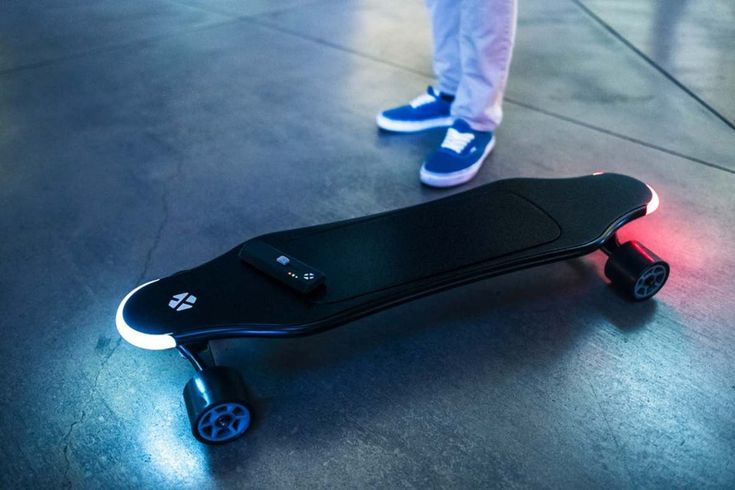 a person standing next to a skateboard with wheels on the floor and lights on