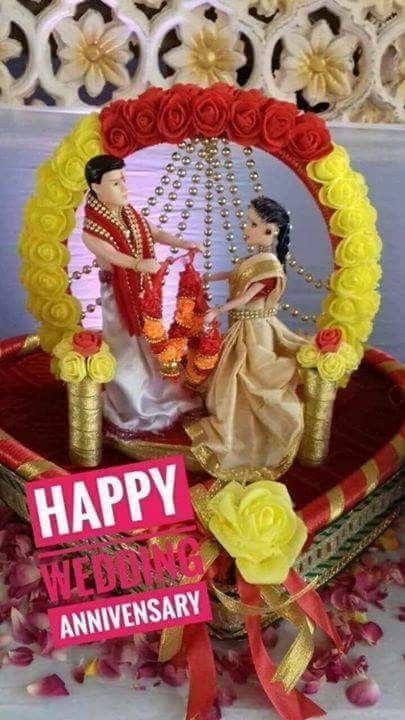 a happy wedding anniversary card with a bride and groom sitting on a swing surrounded by flowers