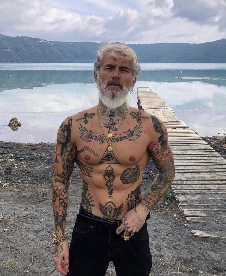 a man with tattoos standing on a dock