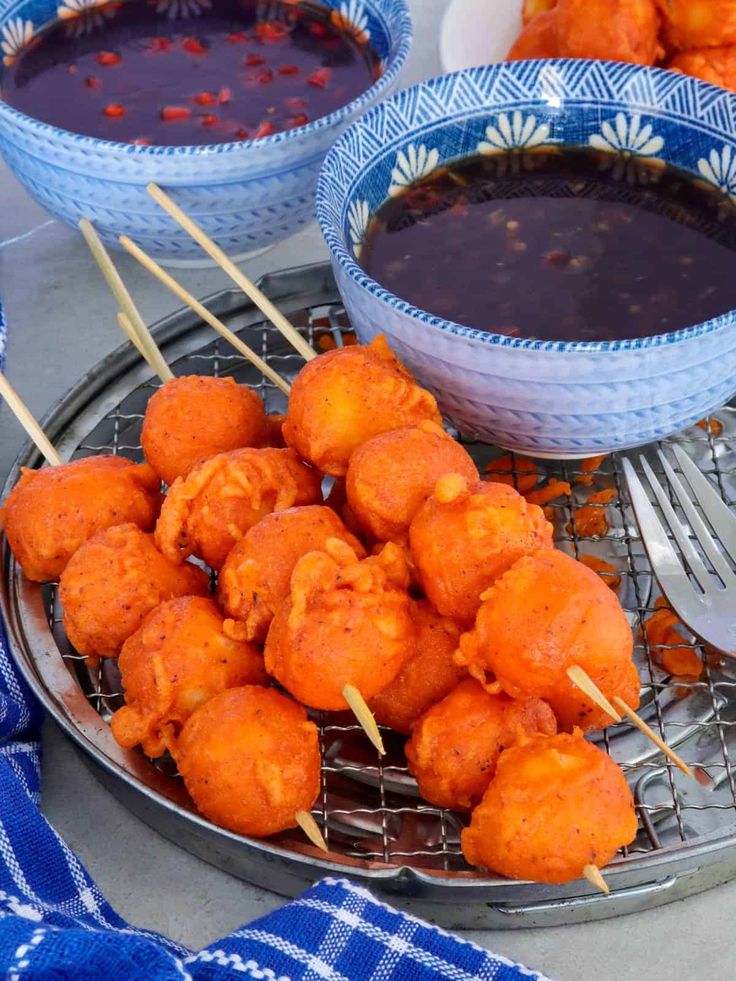 some food is sitting on a plate with toothpicks and sauce in the bowl