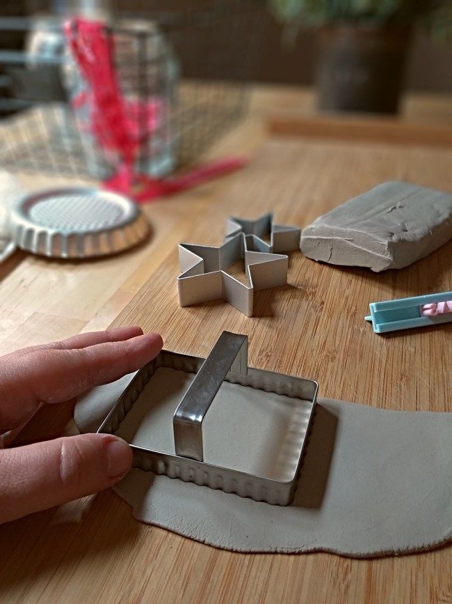 a person is making some kind of cookie cutters on a wooden table with other items