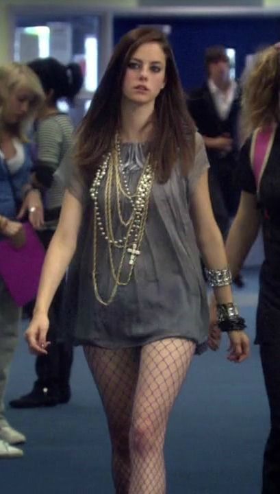 a woman in fishnet tights and heels walking through an airport lobby with other people