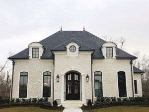 a white brick house with black shutters on the front door and windows in the middle