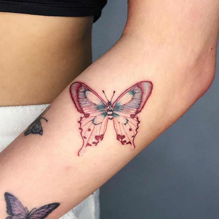 a woman's arm with a butterfly tattoo on the left side of her body