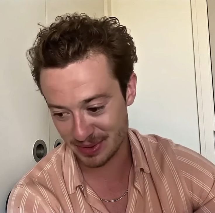 a man is looking down at his cell phone while wearing a striped shirt and smiling