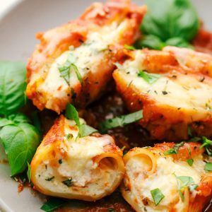 a white plate topped with pasta and spinach covered in marinara sauce, garnished with parsley