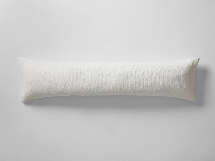 a white pillow sitting on top of a gray wall