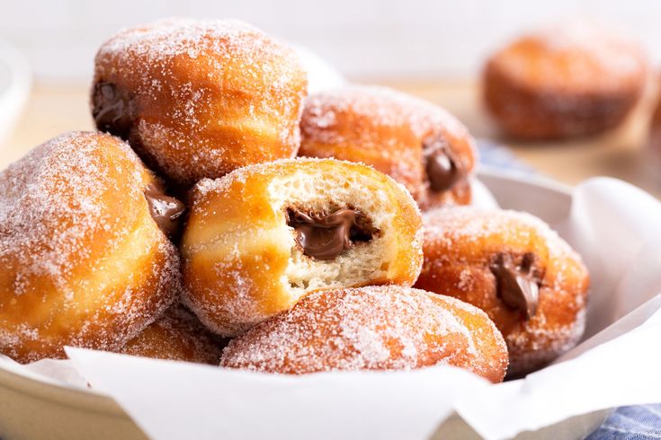 a bowl filled with powdered sugar covered donuts