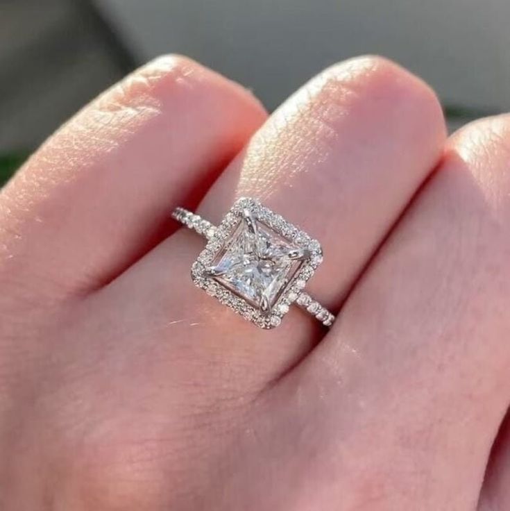 a woman's hand with a diamond ring on top of her finger and an engagement band