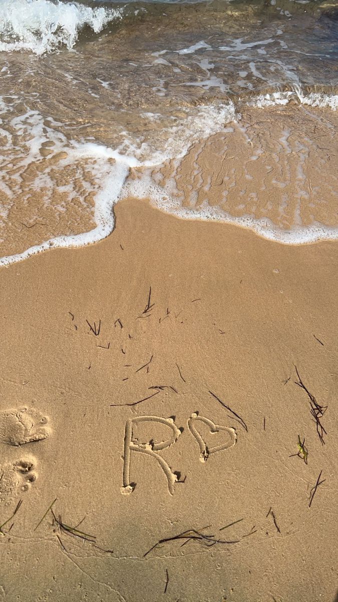 the word love is written in the sand at the beach next to the ocean waves