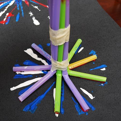 four colored straws are tied together in a starburst pattern on a black table cloth