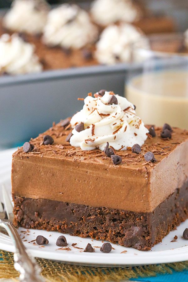 a piece of chocolate cake on a plate with whipped cream and chocolate shavings