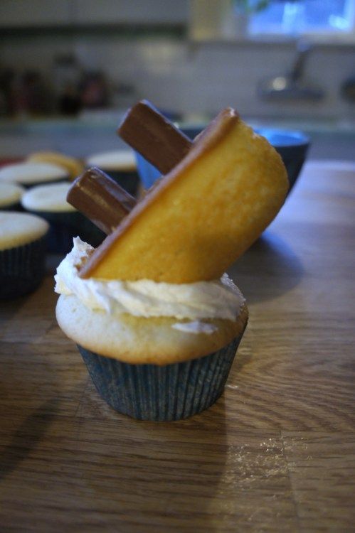 cupcakes with icing and cinnamon sticks sticking out of them on a table