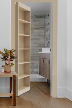 an open door leading to a bathroom with a plant on the table and a sink