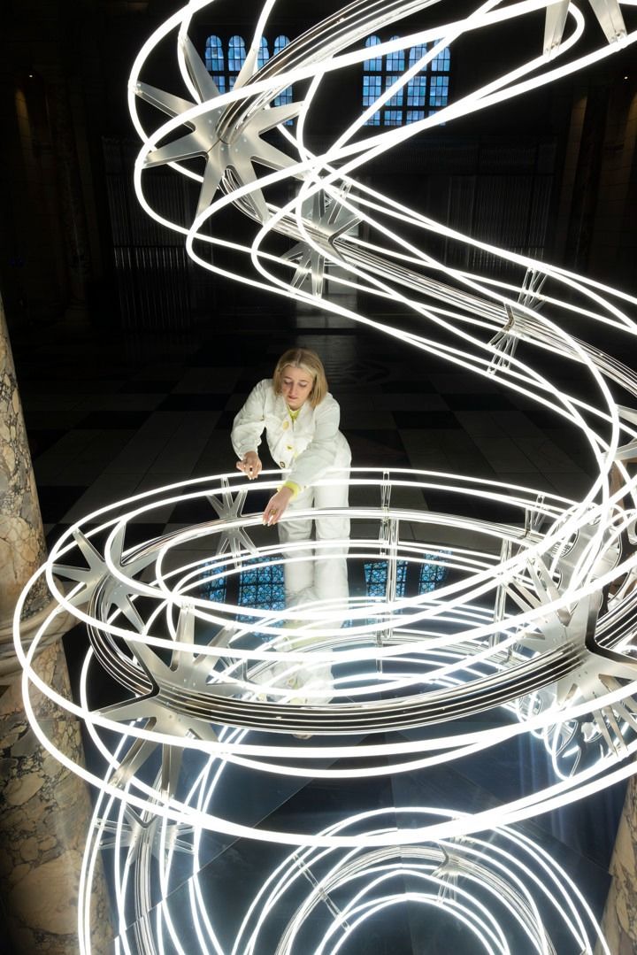 a woman standing in front of a sculpture with white lights