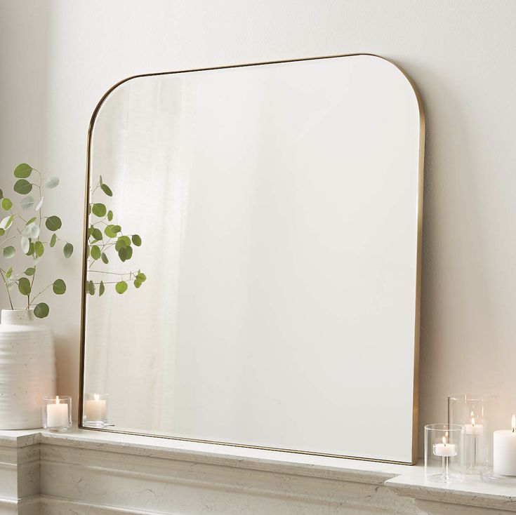 a mirror sitting on top of a mantle next to candles