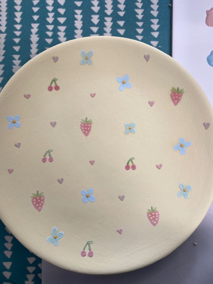 a bowl with hearts and flowers painted on it next to a wallpapered background