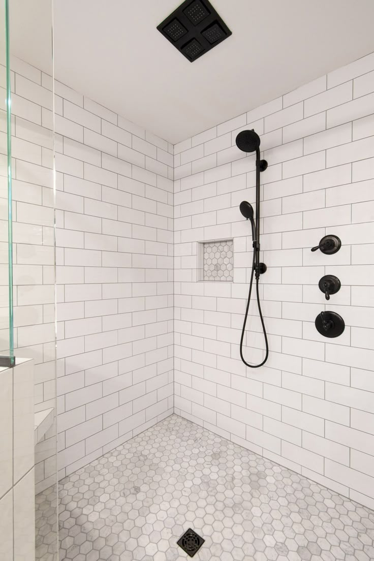 a white tiled bathroom with black fixtures and hexagonal floor tiles on the walls