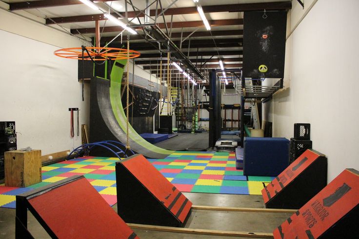 an indoor basketball court with colorful tiles on the floor and hoop in the middle,