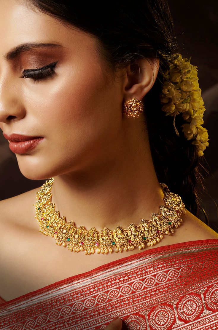 Drawing inspiration from South Indian temple artistry, this necklace set is a true masterpiece. Its design intricately captures the motifs of an Indian goddess, making it a stunning piece of art. The accompanying earrings are equally exquisite, adding a touch of elegance and sophistication to the set. Finish: 22KT Gold Plating Material: Silver, Copper Alloy Color: Gold Size: Free Size, Adjustable Closure Type: Draw String Box Contains: 1 Necklace, 1 Pair Earrings Elegant Temple Jewelry Kundan Necklace, Festive Navratri Jewelry With Matching Earrings, Elegant Design Temple Necklace For Festive Season, Navratri Celebration Jewelry With Matching Earrings, Diwali Temple Jewelry With Matching Earrings, Elegant Temple Necklace For Festive Season, Celebration Jewelry With Matching Earrings For Navratri, Festive Matching Earrings For Navratri, Elegant Necklace For Diwali Rituals