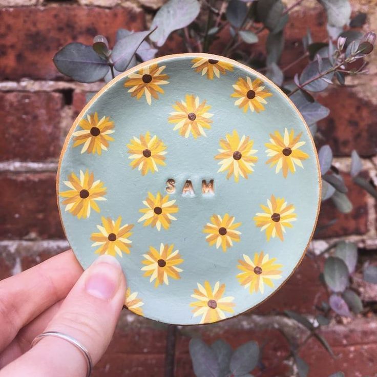 a hand holding a plate with yellow flowers on it