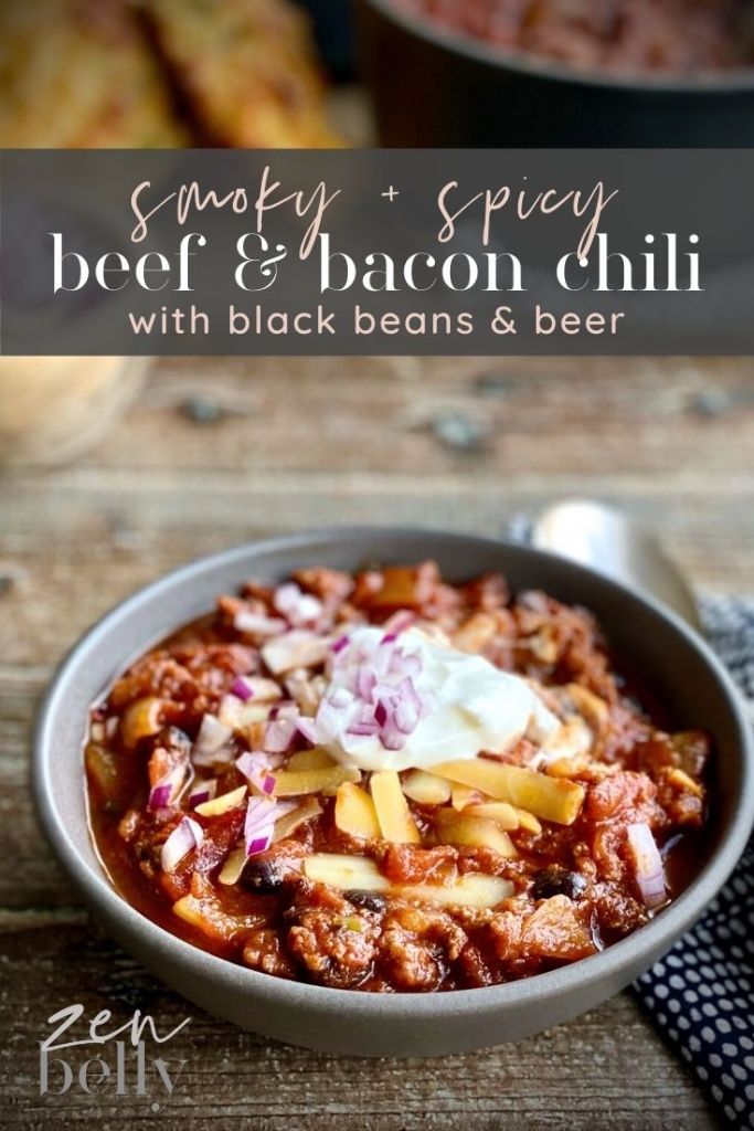 a bowl filled with chili and cheese on top of a wooden table