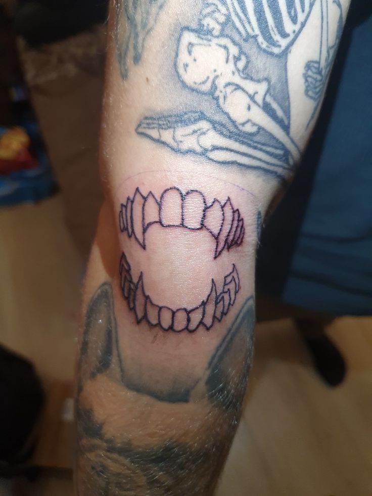 a man with a tattoo on his arm that has teeth and a helmet on it