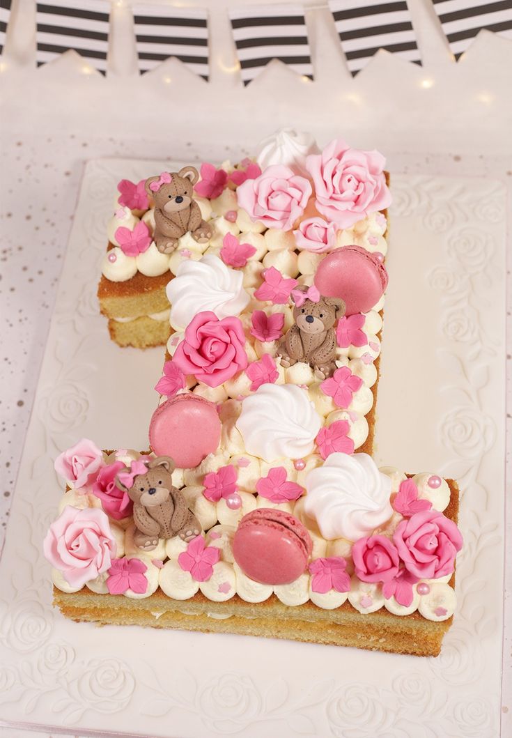 the cake is decorated with teddy bears and pink flowers on it's first birthday