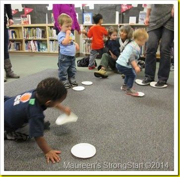 a group of children playing with frisbees on the floor in a library