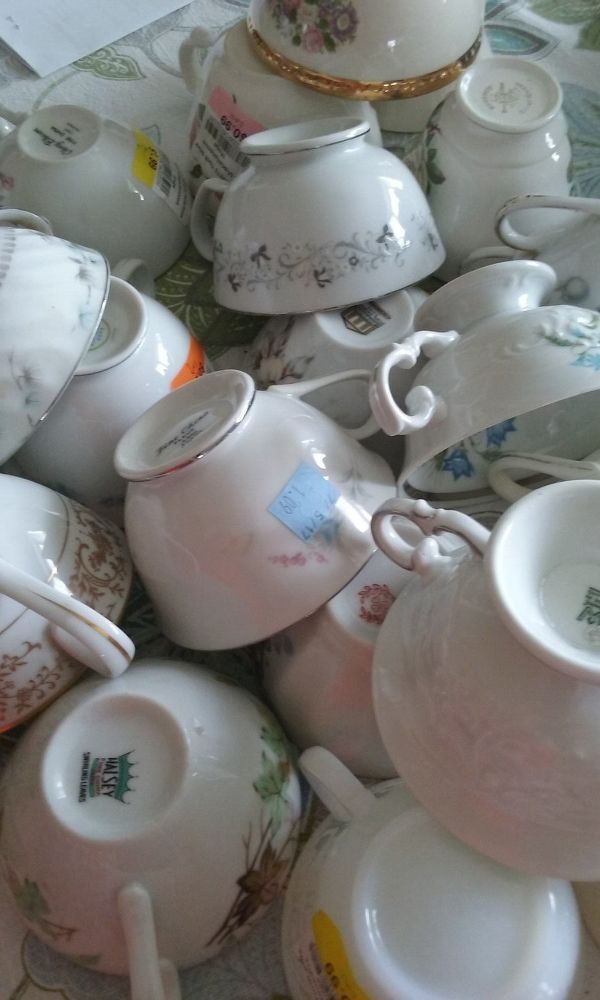 a pile of tea cups and saucers sitting on top of a table next to each other