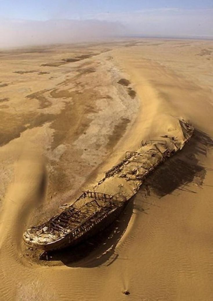 an old boat sitting in the middle of some sand