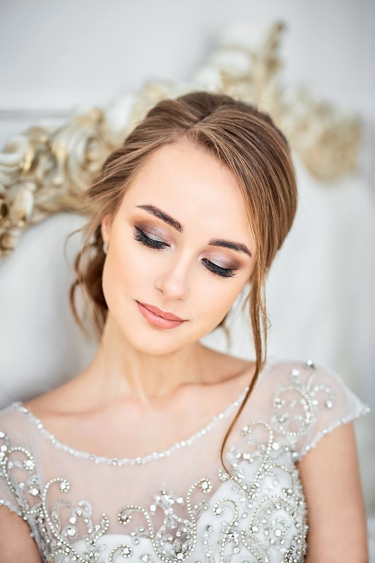 a woman in a wedding dress with her hair pulled back and makeup applied to the side