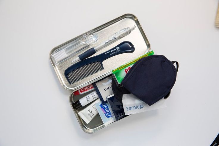 an open metal case with various items in it sitting on a table next to a brush